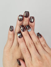 Hand model wearing Naillover Mystic Maroon press on nails Singapore, showing burgundy with blue and gold accents in natural light